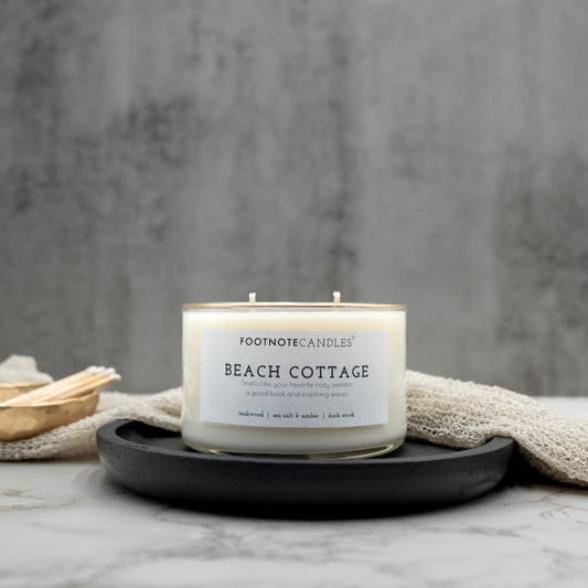 Beach Cottage Candle from Footnote Candles. Candle with hand painted gold rim, on black tray.