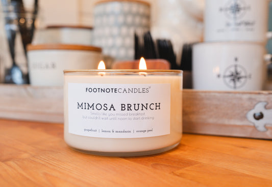 Mimosa Brunch Candle from Footnote Candles. Sitting on wood counter in kitchen.