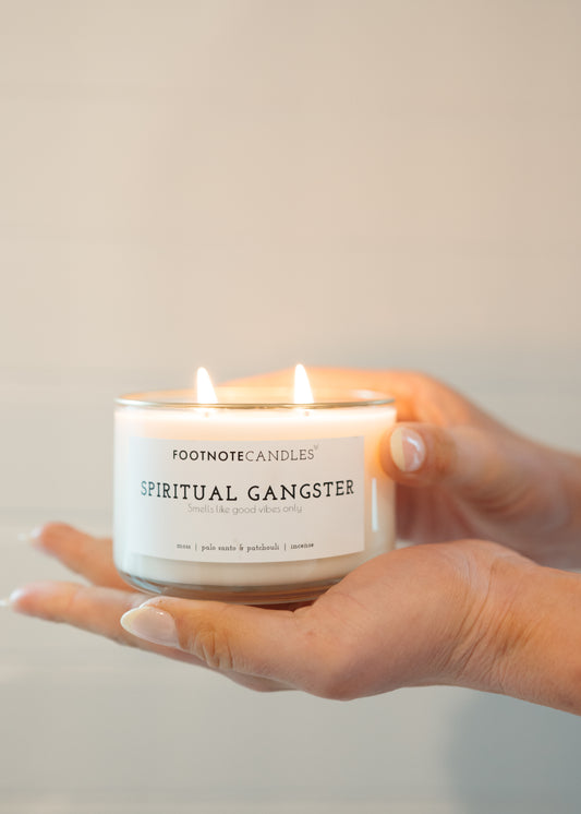 Spiritual Gangster Candle from Footnote Candles. Candle is lit and sitting in the palm of a woman's hand.