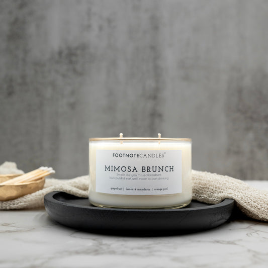 Mimosa Brunch Candle from Footnote Candles. Candle with hand painted gold rim, on black tray.