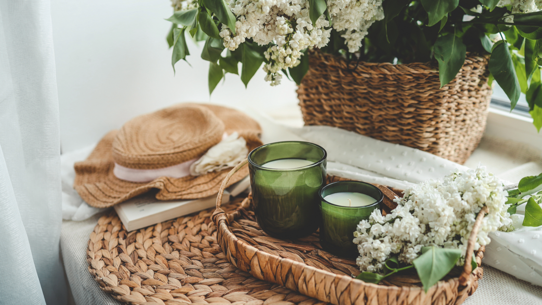 Photo of candles in woven rattan basket, with fresh white flower arrangement.