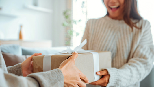 Woman handing a wrapped gift to another woman.