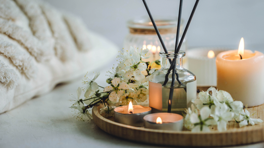 Wood ray with candles of varying sizes, glass reed diffuser and fresh spring flowers.