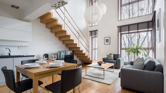 Photo of apartment interior with dining table and chairs, wood stair case and living room furniture