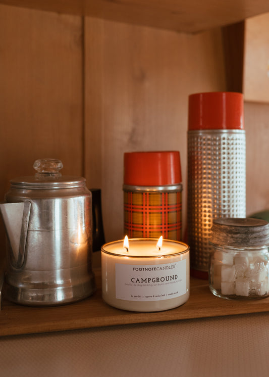 Campground Candle with hand painted gold rim from Footnote Candles. Candle is sitting in camper with vintage camping items.