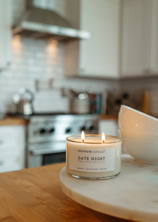 Date Night candle with hand painted gold rim by Footnote Candles. Candle is sitting in a bright white kitchen.