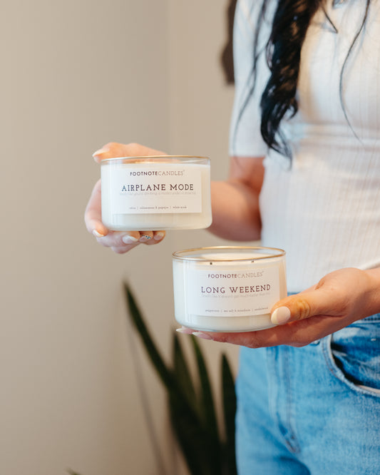 Airplane Mode Candle and Long Weekend Candle from Footnote Candles, being held by woman