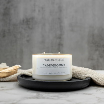 Campground Candle from Footnote Candles. Candle with hand painted gold rim, on black tray.