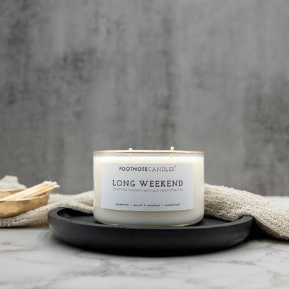 Long Weekend Candle from Footnote Candles. Candle with hand painted gold rim, on black tray.