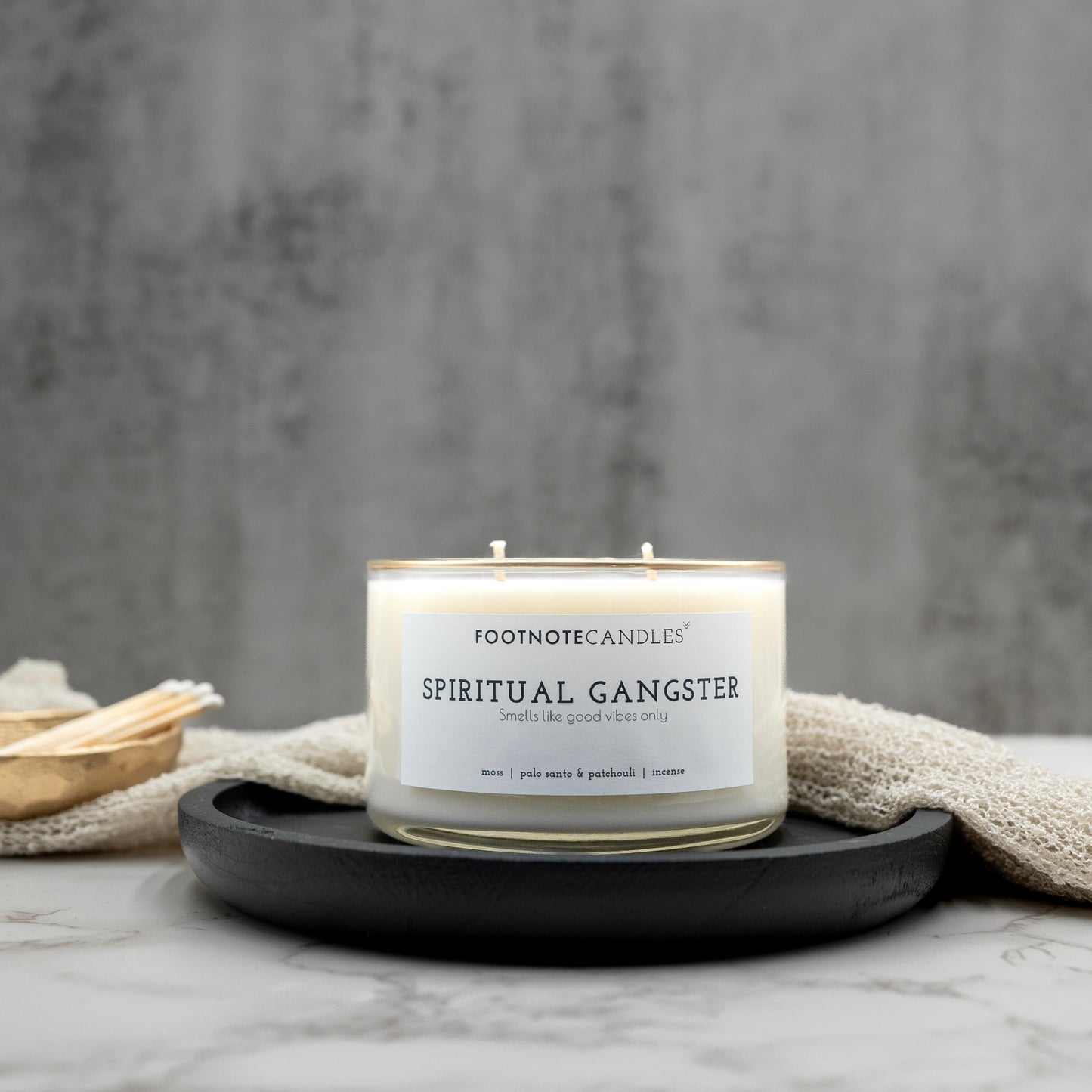 Spiritual Gangster Candle from Footnote Candles. Candle with hand painted gold rim, on black tray.